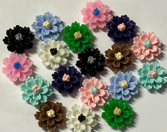 Könnte beinhalten: Sortiment von 18 kleinen Plastikblumen-Verzierungen in verschiedenen Farben, darunter Rosa, Blau, Grün, Weiß und Braun. Jede Blume hat eine erhabene Mitte und mehrere Blütenblätter.