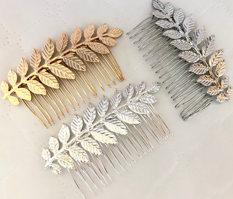 Op de afbeelding: Drie gouden en zilveren haar kammen met bladontwerpen. De kammen zijn gemaakt van metaal en hebben een delicate, vrouwelijke uitstraling.