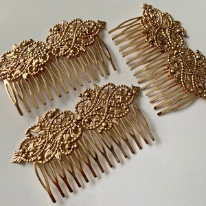 May include: Three gold hair combs with intricate floral designs. Each comb has a decorative top and a row of teeth.