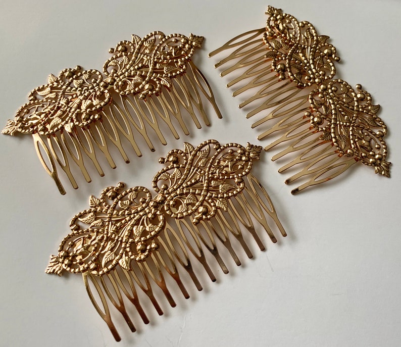 May include: Three gold hair combs with intricate floral designs. Each comb has a decorative top and a row of teeth.