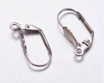 Könnte beinhalten: Zwei silberne Ohrring-Verschlüsse mit Clip-Design. Die Verschlüsse sind aus Metall und haben eine glatte Oberfläche.