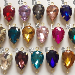 Può includere: Assortimento di 20 perline di vetro a forma di goccia con anelli in metallo dorato. Le perline sono di vari colori, tra cui trasparente, rosso, rosa, nero, blu, verde e oro.