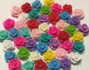 May include: Assortment of colorful plastic rose flower embellishments. The roses are in various shades of pink, purple, blue, green, yellow, red, and white.