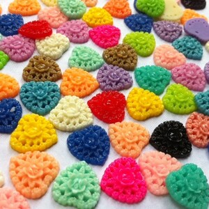 May include: Assortment of colorful heart-shaped resin embellishments with a lace design. The embellishments are in various colors, including pink, blue, green, yellow, red, and white.