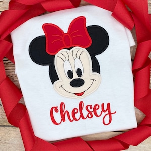 May include: White t-shirt with a red embroidered Minnie Mouse design and the name "Chelsey" in red embroidery.