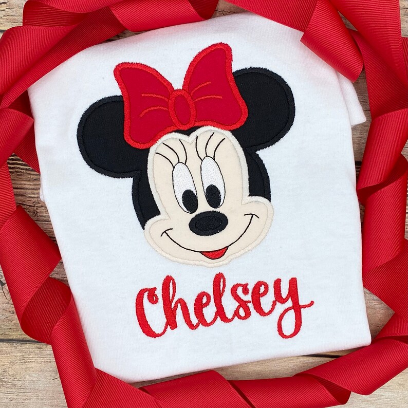 May include: White t-shirt with a red embroidered Minnie Mouse design and the name "Chelsey" in red embroidery.