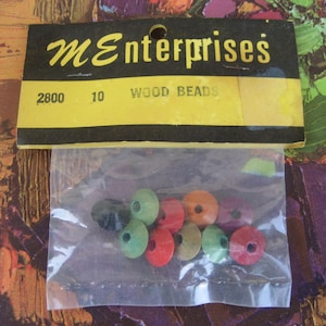 May include: A package of 10 wood beads in assorted colors, including red, green, black, and orange. The package is labeled "ME enterprises" and "2800 10 WOOD BEADS".