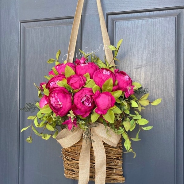 Corona de peonías rosa intenso: decoración primaveral para puertas de estilo rústico.