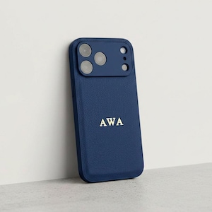 May include: A dark blue textured smartphone case featuring a raised camera module with three circular lenses and a flash. The back of the case is embossed with the gold-coloured letters AWA centred in the lower portion of the phone cover.