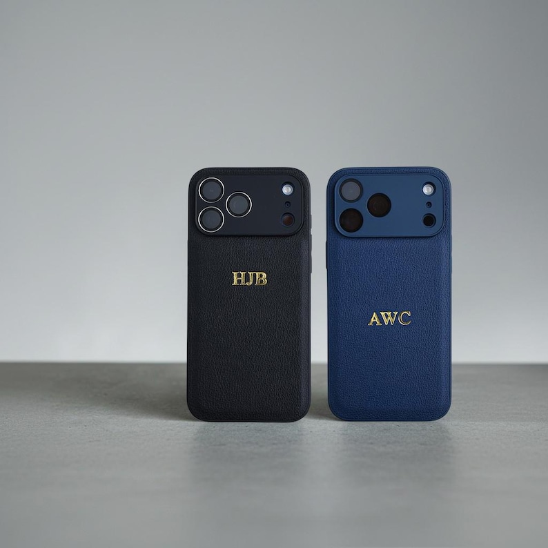 May include: Two textured phone cases, one black and one blue, each featuring a camera cutout and gold embossed initials. The black case displays the letters HJB, while the blue case displays the letters AWC. Both cases have a leather-like finish.