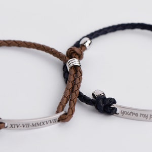 May include: Two braided leather bracelets with silver metal accents. One bracelet has the inscription "XIV-VII-MMXVII" and the other has the inscription "You're my person".