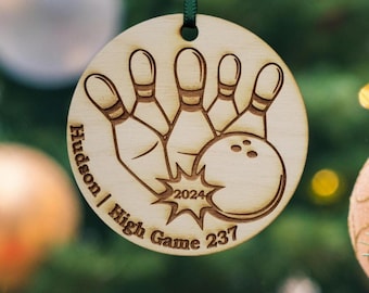 May include: A round wooden ornament with a bowling ball and pins design. The ornament is engraved with the text "Hudson | High Game 237" and "2024".