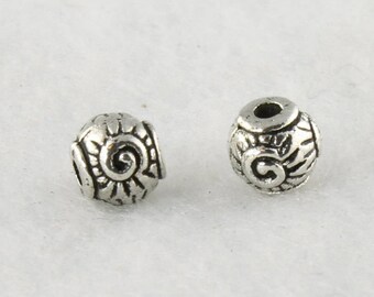 May include: Two silver metal beads with a swirl design. The beads are round and have a hole in the center.