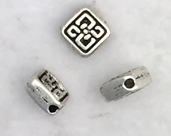May include: Three silver metal beads, one square with a decorative design and two cylindrical with a hole in the center.