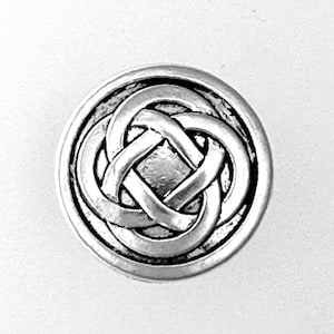May include: A round, silver-toned button with a Celtic knot design. The knot is intricately woven within a circular border, creating a detailed and textured appearance. The button has a slightly aged or antique look.