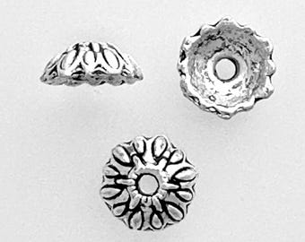May include: Three silver metal bead caps with a decorative design. The caps have a round shape with a hole in the center.