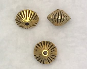 Puede incluir: Tres cuentas de metal de color dorado con un diseño decorativo acanalado. Las cuentas tienen un pequeño agujero en el centro para enhebrar.