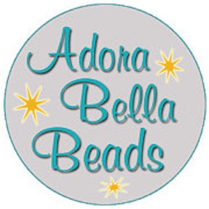 May include: A gray circle with the text "Adora Bella Beads" in teal blue lettering with yellow stars around the text.