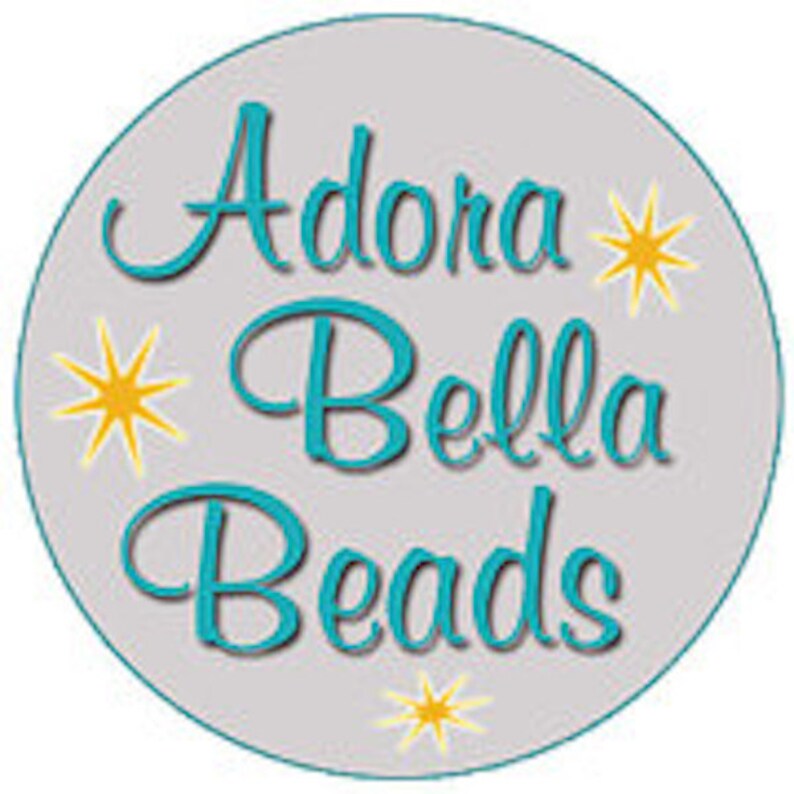 May include: A gray circle with the text "Adora Bella Beads" in teal blue lettering with yellow stars around the text.