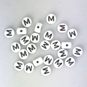 May include: A collection of white plastic letter beads with the letter "M" printed in black.