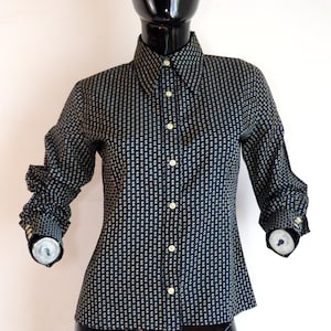 Può includere: Una camicia a maniche lunghe con bottoni e colletto a punta, con motivo bianco e nero.