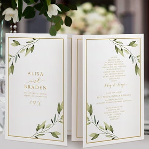 Puede incluir: Una invitación de boda blanca con detalles dorados y hojas verdes de acuarela. La invitación dice "Alisa y Braden" e incluye la fecha y el lugar de la boda. La parte posterior de la invitación incluye un poema sobre el amor y un anuncio de recepción.