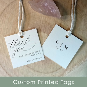 May include: Two white square gift tags with black text. One tag says "Thank you for celebrating with us Olivia & Michael". The other tag says "O | M 8.23.XX".