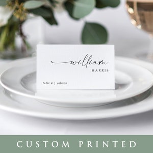 May include: White place card with black calligraphy text that reads "william HARRIS" and "table 4 | salmon".