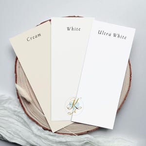 Op de afbeelding: Drie papierstalen op een houten oppervlak. De stalen zijn gelabeld met "Cr&egrave;me", "Wit" en "Ultra Wit".