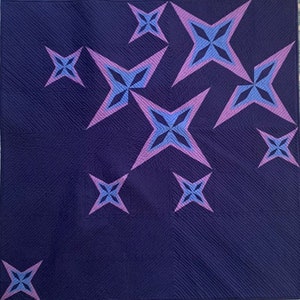 May include: A dark blue quilted fabric with a pattern of pink and blue stars. The stars are arranged in a diagonal pattern across the fabric.