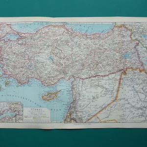 以下が含まれることがあります： TÜRKEI KLEINASIENと題されたヴィンテージの印刷地図。トルコとその周辺地域の地理が示されています。地図には詳細な地形、海岸線、境界線が落ち着いた色調で描かれており、下部には小さな挿入図と凡例が含まれています。