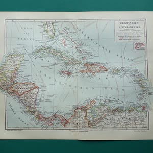 May include: An antique paper map titled Westindien und Mittelamerika, depicting the Caribbean and Central America with light blue oceans and tan landmasses. The map features detailed black text, red borders, and a legend in the upper right corner.