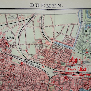 May include: A detailed vintage map of Bremen, Germany, with the city name at the top. The map features red and black lines indicating streets and railways, with areas colored in shades of pink and green. Text labels identify various locations.