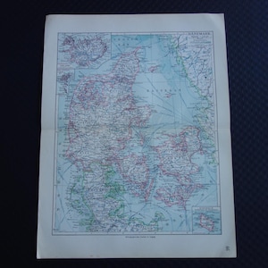May include: A vintage map of Denmark, Iceland, and surrounding areas. The map features detailed coastlines, cities, and geographical features, with text in German. The map is printed on aged paper with a light blue and green color palette.