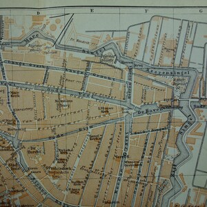 May include: An antique map fragment, featuring a detailed street plan with canals and labeled streets. The map uses a sepia-toned color palette with black text, showcasing a vintage aesthetic. The map's grid system is visible.