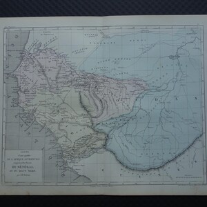 Op de afbeelding: Antieke kaart van de rivier de Senegal en omgeving, met gedetailleerde geografische kenmerken. De kaart is gedrukt op verouderd papier en heeft een raster en Franse tekst. De kleuren van de kaart omvatten tinten blauw, roze en grijs.