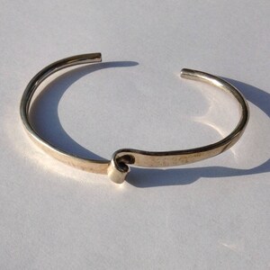May include: A silver bangle bracelet with a twisted design.