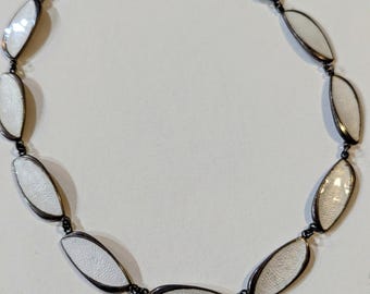 May include: A white enamel and silver necklace with a chain of oval-shaped links. Each link is outlined in silver and has a white enamel center.