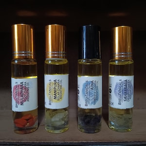 May include: Four small glass bottles with gold lids and labels. Each bottle contains a clear liquid and crystals. The labels read "BREU TANICALS" and the name of a chakra, such as "MULADHARA" and "MANIPURA".