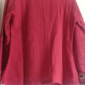 以下が含まれることがあります： 赤い長袖シャツ、刺繍入りの襟と袖口が特徴です。 襟と袖口には、茶色、黄色、緑色の詳細な模様があります。 シャツは柔らかく流れるような生地で作られています。