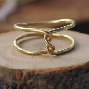 May include: A gold-toned ring with a twisted design. The ring is made of two bands that are intertwined.