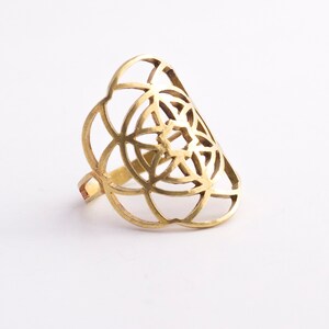 Puede incluir: Un anillo de color dorado con un dise&ntilde;o geom&eacute;trico. El anillo est&aacute; hecho de metal y tiene un patr&oacute;n delicado e intrincado.