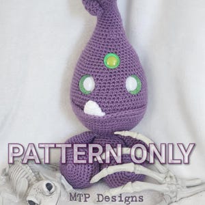 May include: Crochet pattern for a purple amigurumi character with green eyes and a white mouth. The pattern is called "PATTERN-ONLY" and is by MTP Designs.