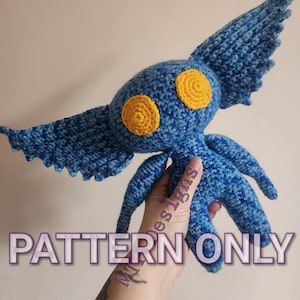 Könnte beinhalten: Häkelmuster für eine blaue und gelbe Amigurumi-Kreatur mit großen Augen und Flügeln. Das Muster ist zum Verkauf, das fertige Produkt ist nicht enthalten. "PATTERN ONLY" ist in lila Schrift auf dem Bild geschrieben.