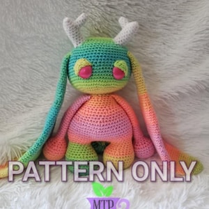Peut inclure: Un modèle de crochet pour un lapin amigurumi de couleur arc-en-ciel avec des bois. Le modèle s'appelle "PATTERN ONLY" et est de MTP Designs.