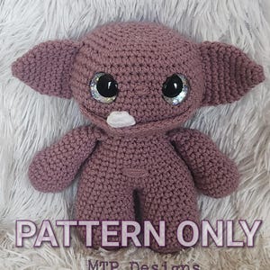 Op de afbeelding: Een haakpatroon voor een pluche speelgoed, met een roze, gehaakte creatuur met grote, glinsterende ogen. Het patroon is getiteld "PATTERN ONLY" met de tekst "MTP Designs" eronder.
