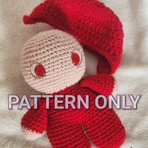 May include: A handmade crochet doll with a red body, arms, and legs, and a matching pointed hat. The doll has a beige head with large red eyes. The text "PATTERN ONLY" is visible on the image. The doll is lying on a white surface.