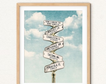 May include: A vintage-style illustration of a signpost with multiple directional arrows pointing to different cities. The signpost reads "Home is where the Army sends us" and lists cities including Monterey, CA, Charleston, SC, Anchorage, AK, Tacoma, WA, and Pensacola, FL.