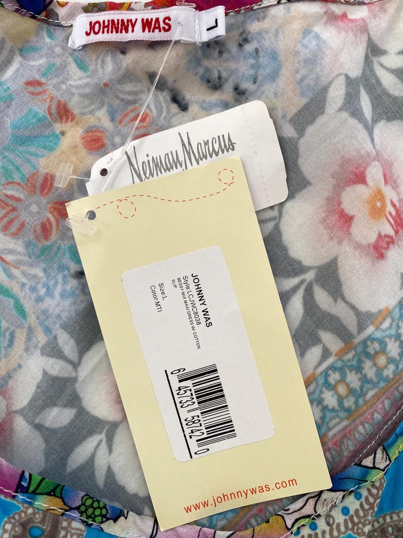 Puede incluir: Un vestido largo con estampado floral con etiquetas de Johnny Was y Neiman Marcus. El vestido presenta un colorido estampado floral. La etiqueta indica el estilo LCJWC8038, talla L y color MTI. El sitio web www.johnnywas.com es visible.