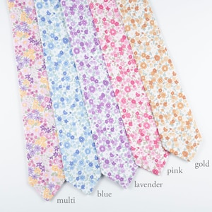 May include: Five floral patterned neckties in shades of pink, purple, blue, and gold. The ties are arranged diagonally, showcasing the delicate flower print. The labels at the bottom read "multi", "blue", "lavender", "pink", and "gold".